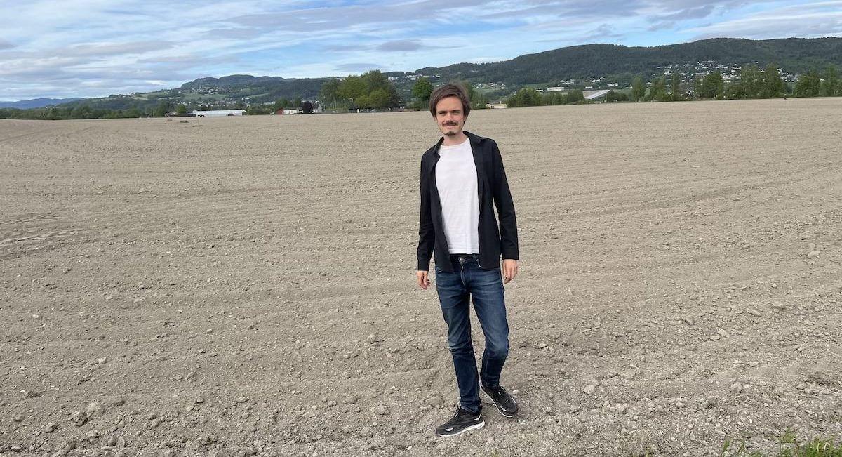 Herman Ekle Lund staar paa et jorde med blaa himmel over