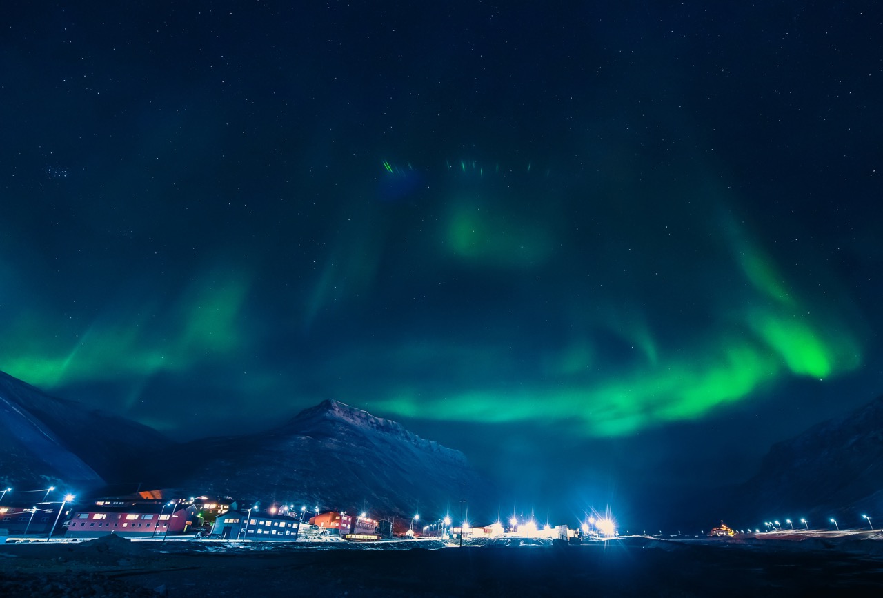 Nordlys lyser opp Longyearbyen under polarnatta – et sterkt lokalsamfunn der lokaldemokratiet er avgjørende for å møte unike utfordringer og sikre norsk tilstedeværelse på Svalbard