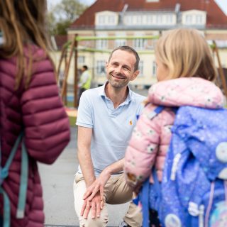 Hallstein Bjercke i skolegård lytter to skoleelever