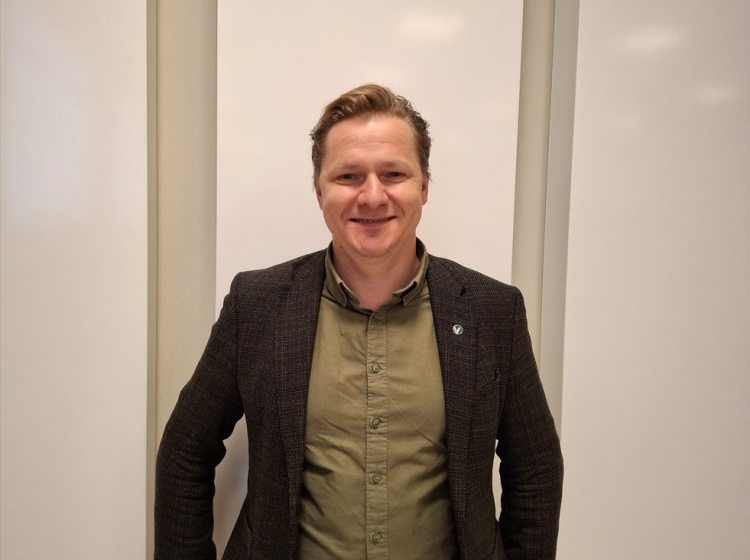 Mann i sort dressjakke og lyst hår