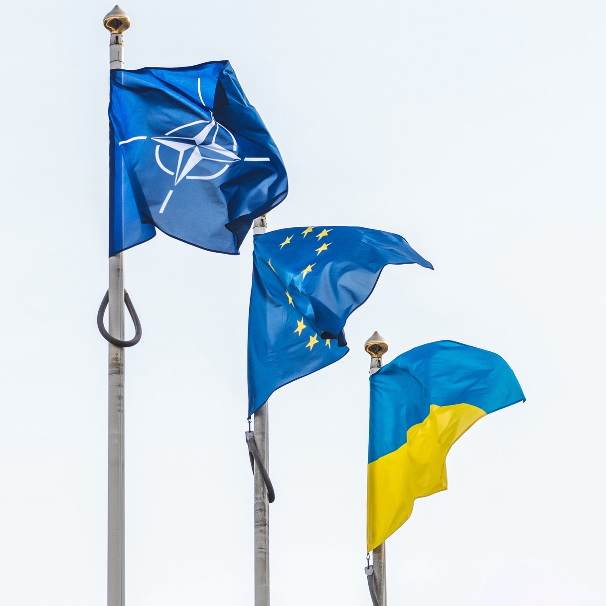 Bilde av tre flaggstenger som flagger med natoflagget, Eu-flagget og det Ukrainske flagget. Side ved side.