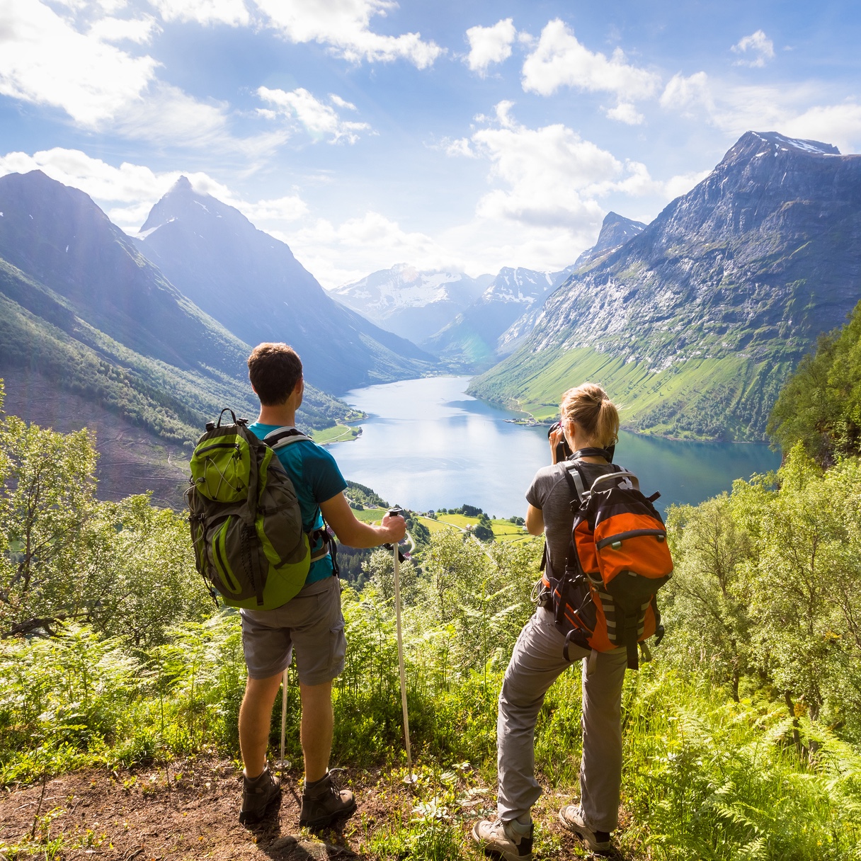 Illustrasjonfoto av to unge turgåere som ser utover praktfult vestnorsk landskap med fjord og spisse fjell