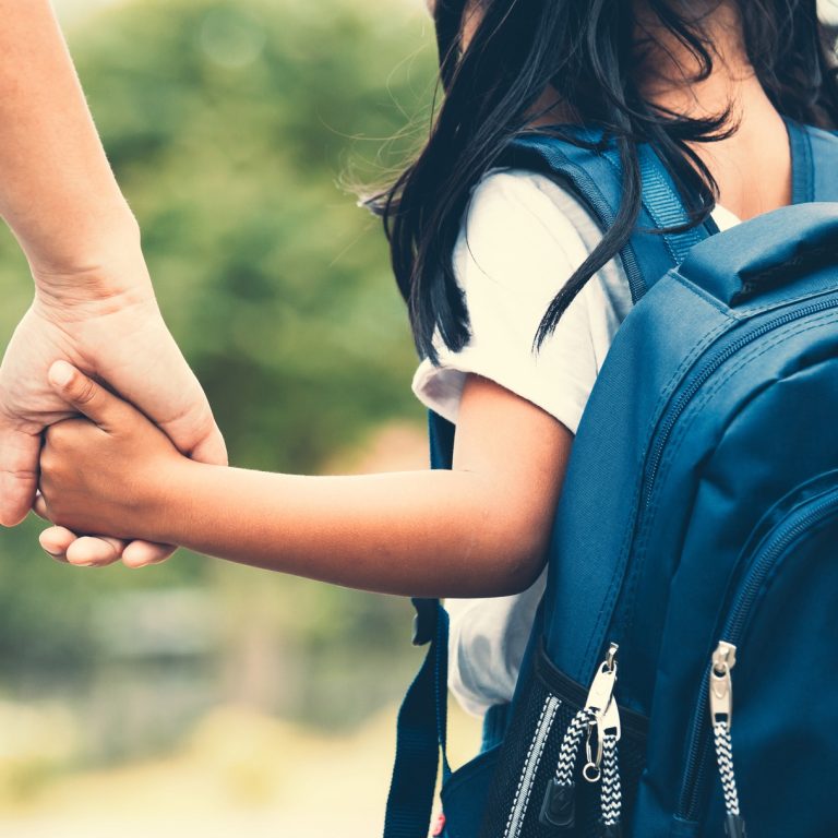 Skolejente på vei til skolen. holder en forelder i hånden.