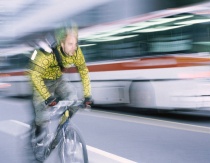 Mann som sykler med buss i bakgrunnen